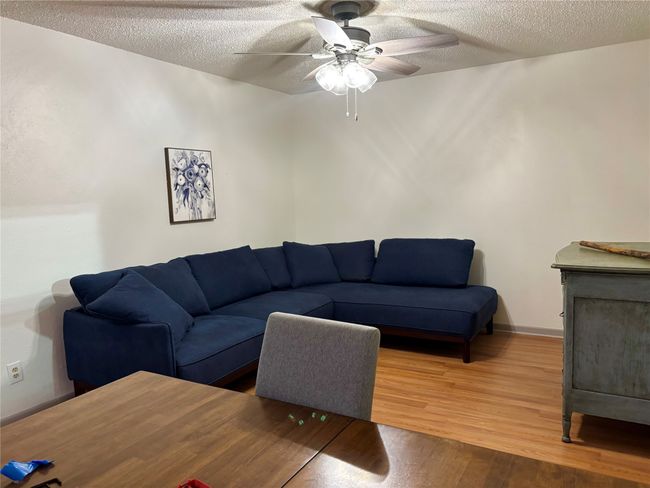 Den with a textured ceiling, wood finished floors, and a ceiling fan | Image 12