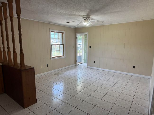 Spare room featuring ceiling fan, light tile patterned flooring, ornamental molding, baseboards, and a textured ceiling | Image 4