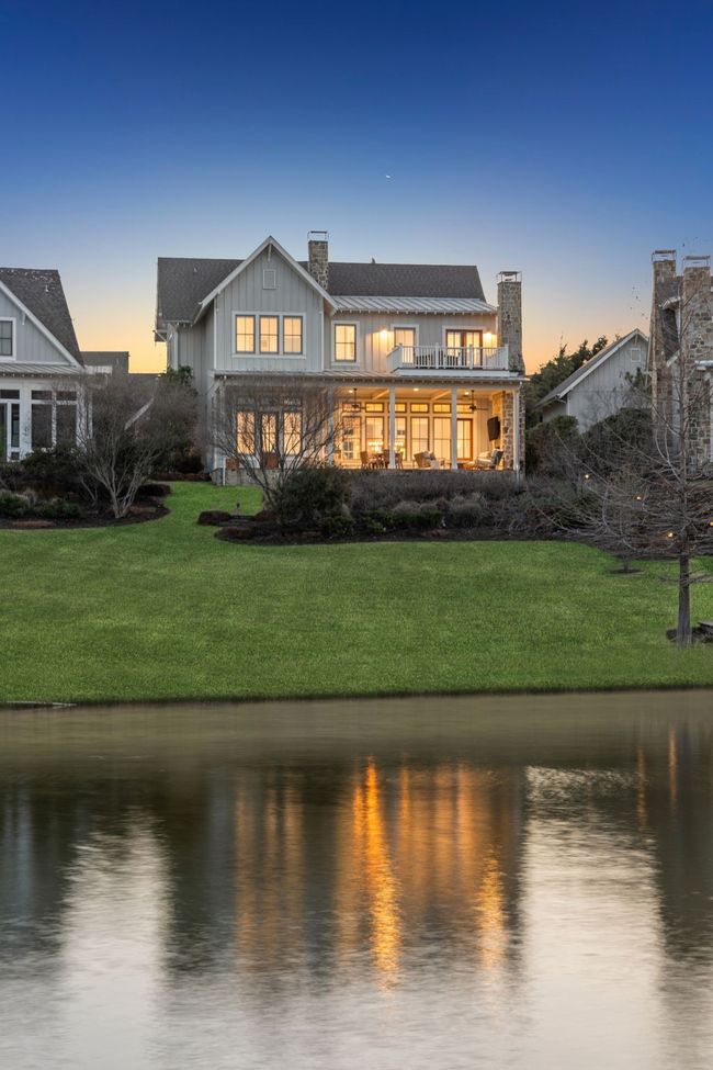 Back of property with a chimney, board and batten siding, metal roof, a lawn, and a water view | Image 39