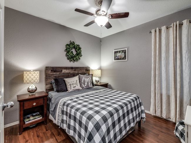 Bedroom featuring wood finished floors, a textured wall, ceiling fan, and baseboards | Image 21