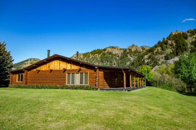 View of property exterior with log exterior, a mountain view, and a yard | Image 53