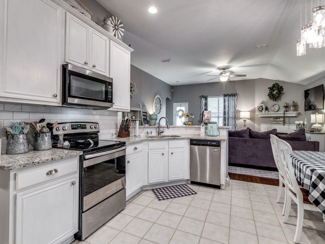 Kitchen featuring appliances with stainless steel finishes, a sink, open floor plan, a peninsula, and decorative backsplash | Image 15