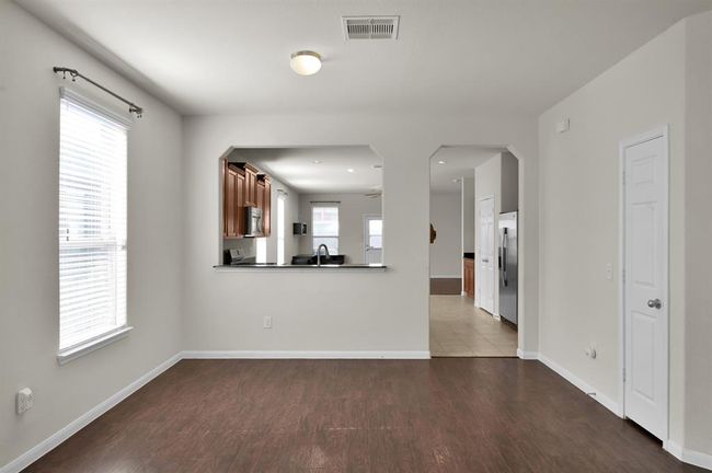 Bright, open-concept kitchen and dining area with hardwood floors and ample natural light. The kitchen features stainless steel appliances and dark wood cabinetry, offering a modern and inviting space for cooking and entertaining. | Image 8