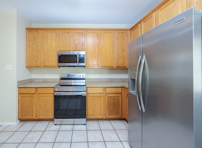 Kitchen with appliances with stainless steel finishes, light countertops, and light tile patterned floors | Image 15