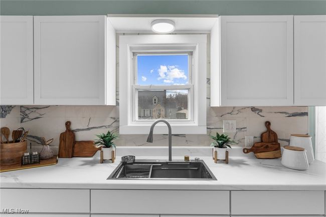 Kitchen with white cabinetry, sink, and backsplash | Image 8