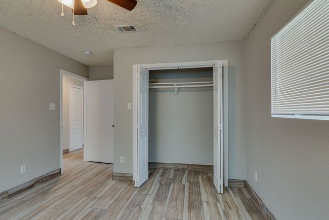 Unfurnished bedroom featuring visible vents, light wood-style floors, a textured ceiling, and a closet | Image 14