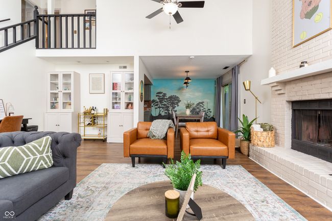 living area featuring a high ceiling, dark wood-style flooring, ceiling fan, a brick fireplace, and built in features | Image 10