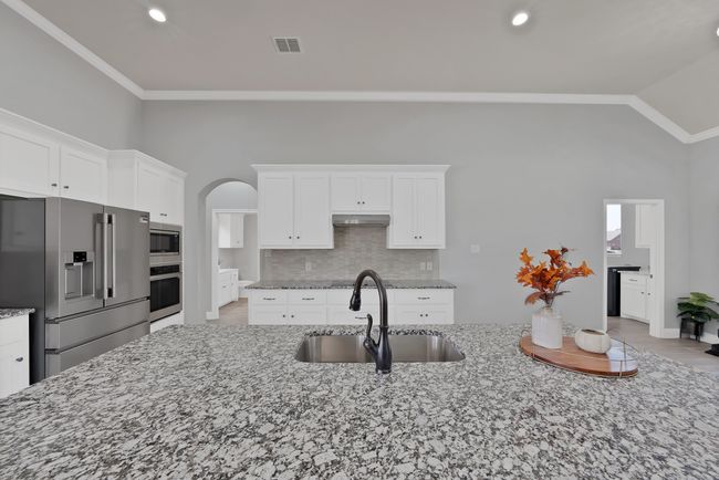 Kitchen featuring appliances with stainless steel finishes, a sink, under cabinet range hood, tasteful backsplash, and arched walkways | Image 7