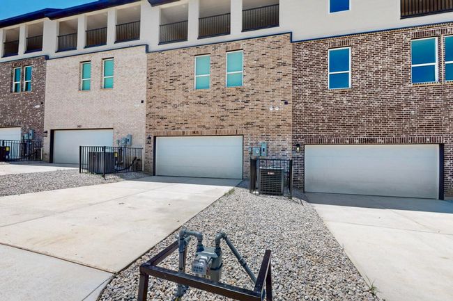 View of front of home with concrete driveway, an attached garage, and brick siding | Image 39