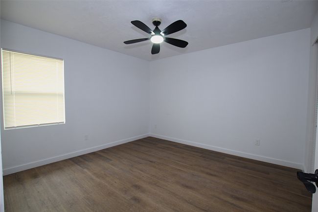 Spare room featuring dark wood finished floors, baseboards, and a ceiling fan | Image 9