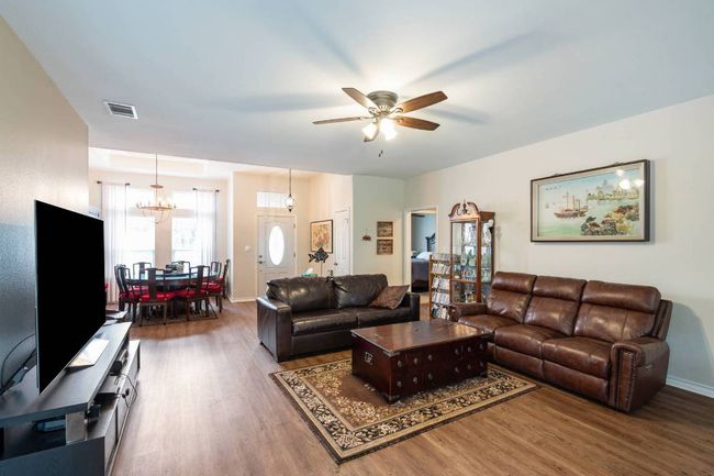 Living room featuring baseboards, wood finished floors, visible vents, and ceiling fan with notable chandelier | Image 19