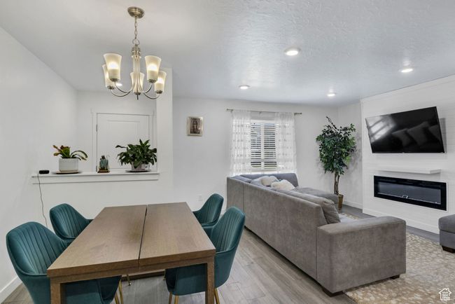 Dining area with a chandelier, wood finished floors, a glass covered fireplace, baseboards, and recessed lighting | Image 8