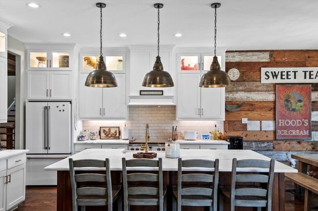 Kitchen with freestanding refrigerator, light countertops, backsplash, a kitchen island with sink, and recessed lighting | Image 15