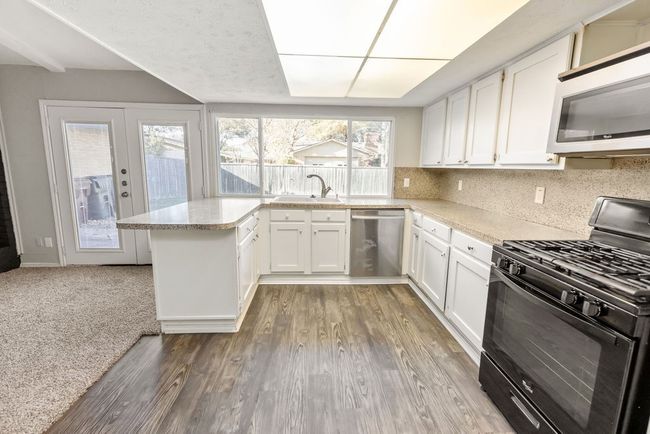 Kitchen featuring white cabinetry, gas stove, a sink, dishwasher, and white microwave | Image 34