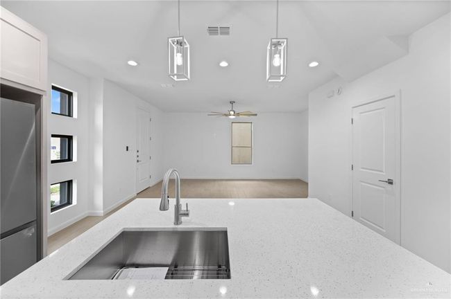 Kitchen featuring freestanding refrigerator, pendant lighting, recessed lighting, light stone countertops, and open floor plan | Image 8