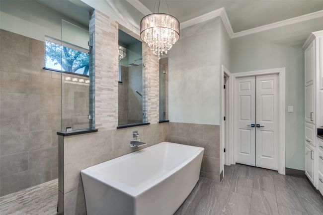 Bathroom featuring a walk in shower, tile walls, a soaking tub, ornamental molding, and a chandelier | Image 23