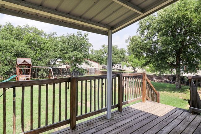 Wooden terrace with a fenced backyard and a playground | Image 4