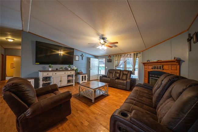 Living room featuring light hardwood / wood-style flooring, ceiling fan, a textured ceiling, and lofted ceiling | Image 14