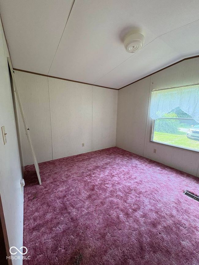 empty room featuring carpet, lofted ceiling, and wooden walls | Image 16