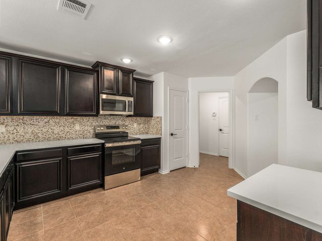 Kitchen with stainless steel appliances, decorative backsplash, light countertops, light tile patterned flooring, and recessed lighting | Image 14