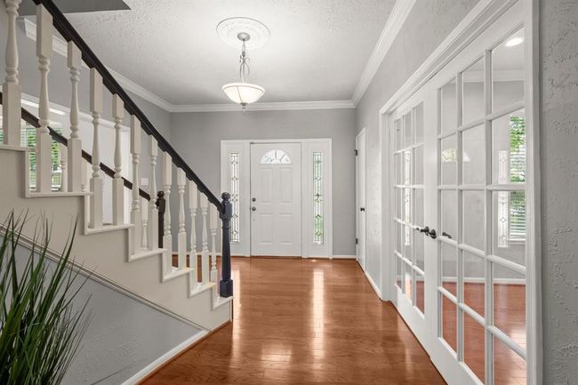 A neutral paint palette, detailed crown molding, and a lovely chandelier in the foyer create a timeless first impression. | Image 4