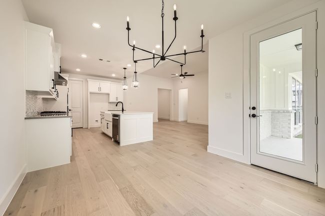 Kitchen featuring a chandelier, tasteful backsplash, recessed lighting, open floor plan, and white cabinetry | Image 8