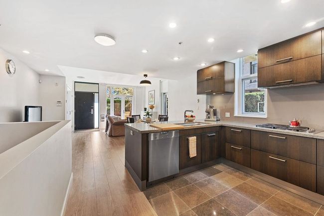 Kitchen featuring dark brown cabinetry, a peninsula, high end appliances with stainless steel finishes, a large size sink | Image 22