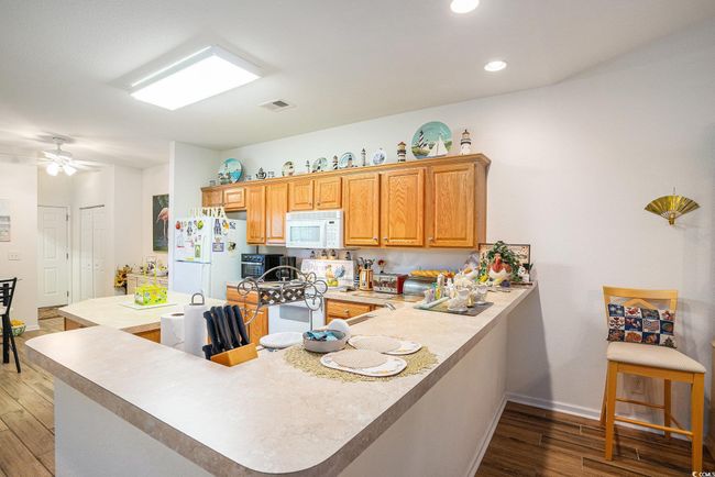 Kitchen featuring white appliances, light wood-type flooring, light countertops, a peninsula, and recessed lighting | Image 9