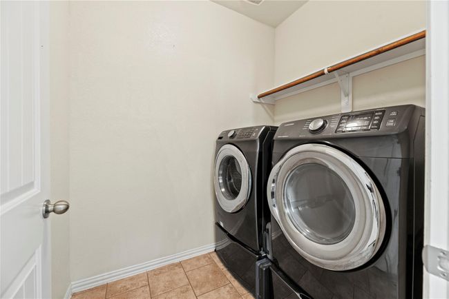 Boasting a laundry room with a hanging bar and a shelf, there is a load of room for cleaning supplies and clothing organization. | Image 21