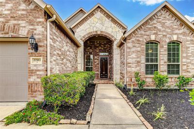 A beautifully landscaped pathway leads to the beautiful brick and stone archway and covered porch. Create a welcoming space by adding your own special touch with a small sitting area, large planter and welcome mat. | Image 2