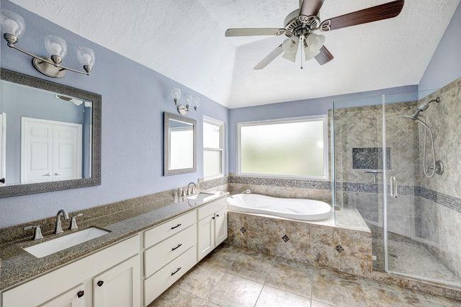 The serene primary bath has double sinks, a soaking tub, and a glass enclosed shower. A large walk-in closet is to the right of the photo. | Image 11