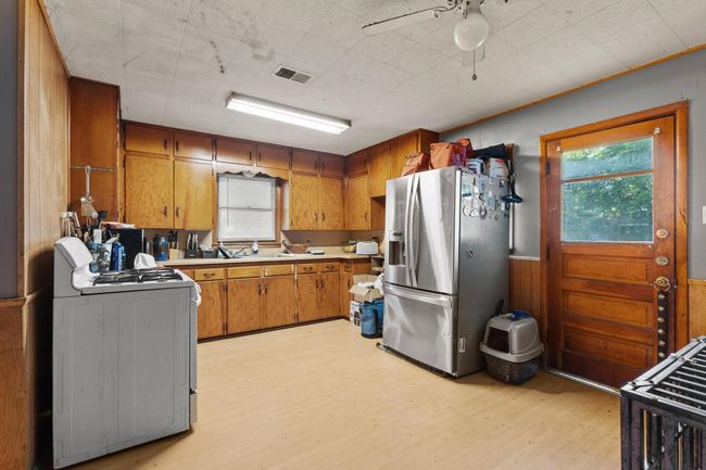 Kitchen with white gas range, stainless steel refrigerator with ice dispenser, light wood finished floors, brown cabinetry, and plenty of natural light | Image 7
