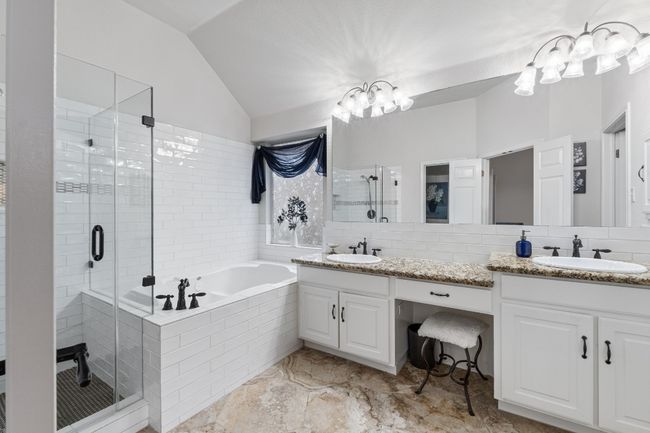 Full bathroom featuring double vanity, a chandelier, a shower stall, vaulted ceiling, and a garden tub | Image 22