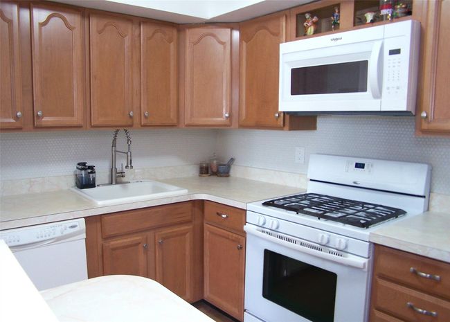 Kitchen with white appliances, a sink, light countertops, and brown cabinets | Image 7