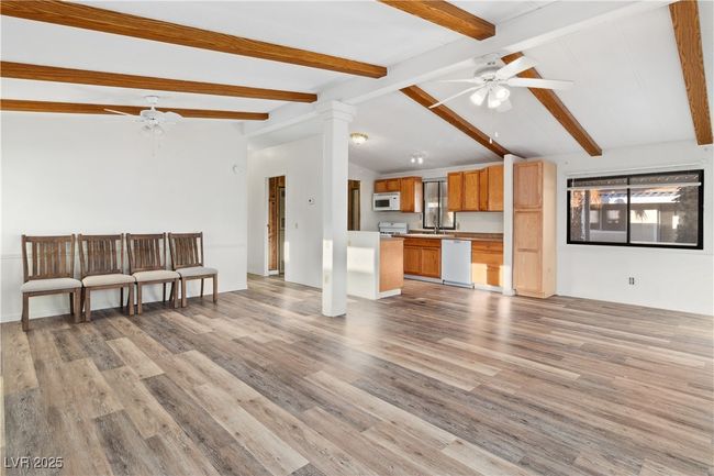 Unfurnished living room with vaulted ceiling with beams, wood style floors, a ceiling fan, and ornate columns | Image 8