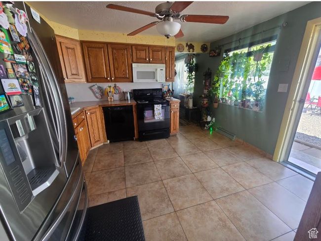 Kitchen with brown cabinetry, a ceiling fan, black appliances, and a healthy amount of sunlight | Image 8