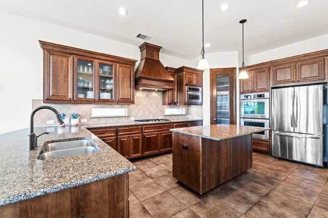 Prepare a feast in the kitchen with expansive granite counters, stainless steel appliances, and five burner gas cooktop. | Image 9