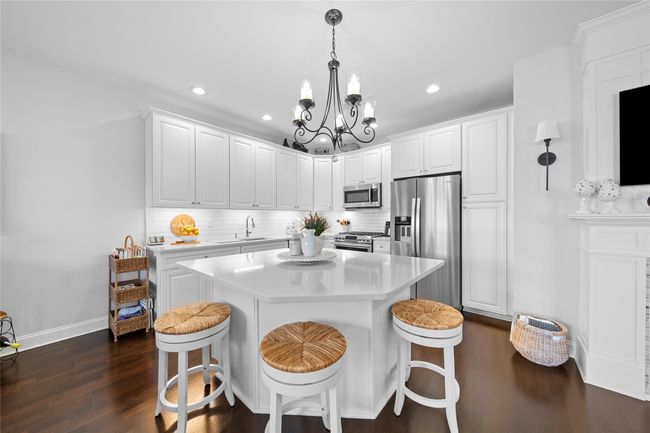 Kitchen with an inviting chandelier, stainless steel appliances, backsplash, and dark wood finished floors | Image 6