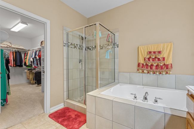 Full bath with a stall shower, a garden tub, a walk in closet, and tile patterned flooring | Image 19