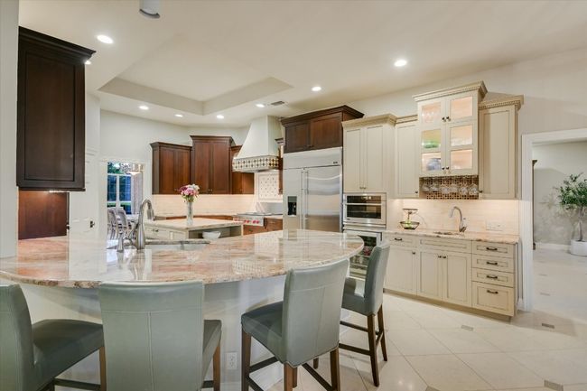 Kitchen with a sink, light stone countertops, stainless steel built in fridge, and custom range hood | Image 5