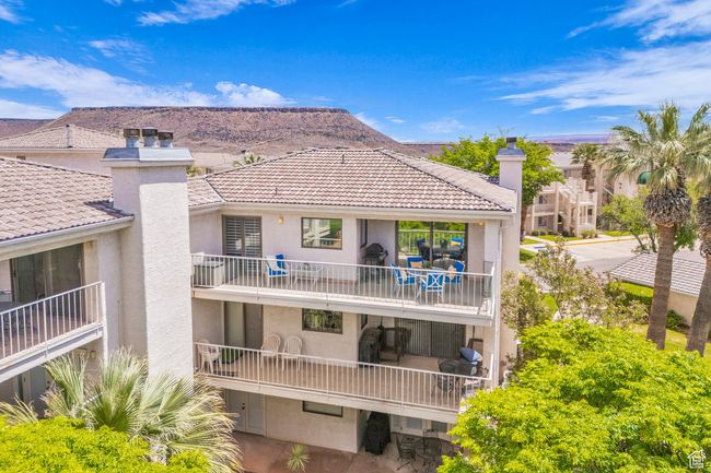 Rear view of property with a chimney, a balcony, stucco siding, and a tile roof | Image 12
