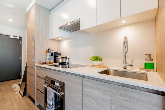 Kitchen with a sink, oven, under cabinet range hood, black electric cooktop, and modern cabinets | Image 8