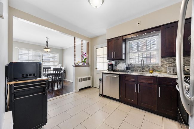 Kitchen with radiator, a sink, crown molding, backsplash, and dishwasher | Image 5