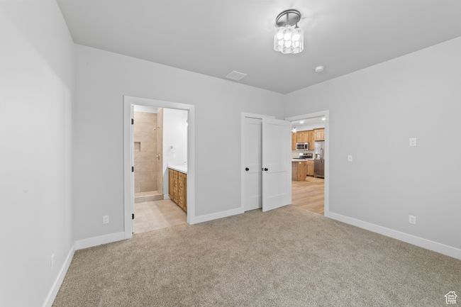 Unfurnished bedroom featuring stainless steel fridge with ice dispenser, baseboards, light colored carpet, and visible vents | Image 30