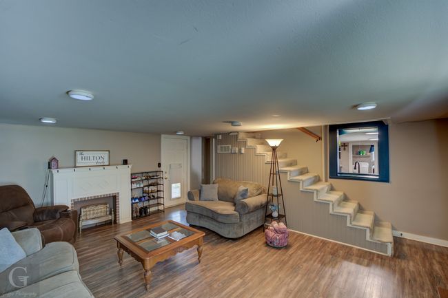 Living room featuring wood finished floors, stairs, baseboards, and a fireplace | Image 9