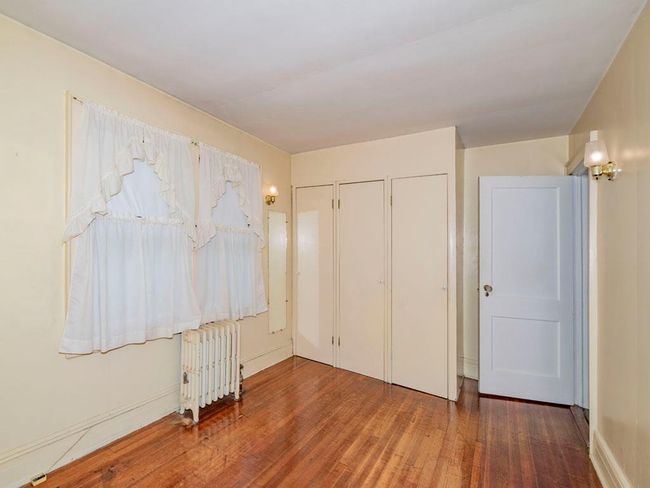 Unfurnished bedroom with radiator heating unit, hardwood / wood-style floors, and multiple closets | Image 27