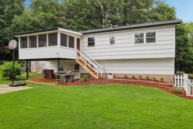 Rear view of property featuring a patio, a sunroom, a chimney, stairs, and a shingled roof | Image 30