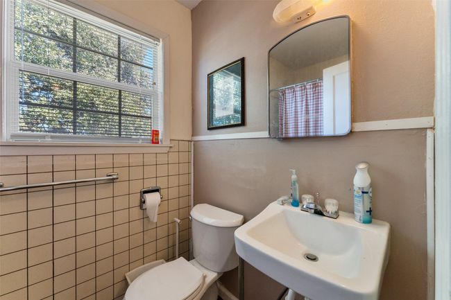 Full bathroom featuring a sink, a shower with curtain, toilet, and wainscoting | Image 15