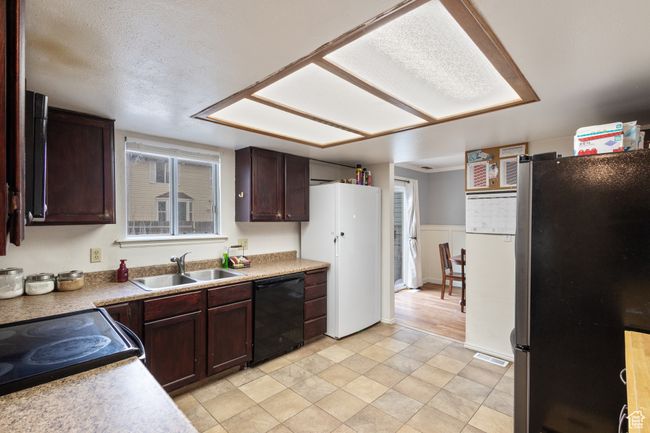 Kitchen with freestanding refrigerator, dishwasher, dark brown cabinets, and light countertops | Image 7