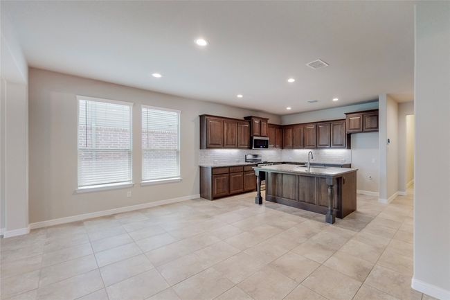 Kitchen featuring backsplash, a sink, light tile patterned floors, a breakfast bar area, and recessed lighting | Image 10